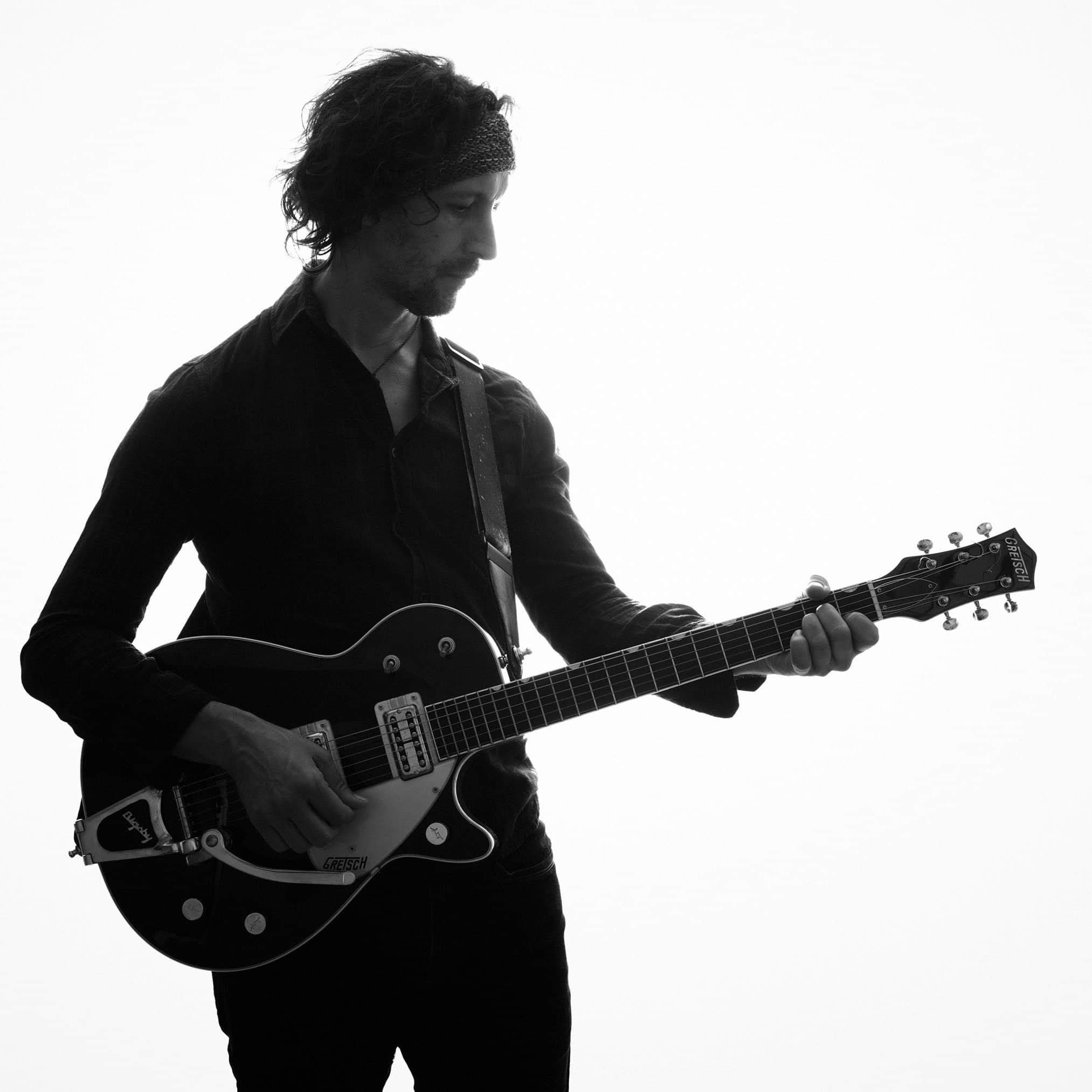 Black-and-white portrait of the artist playing a Gretsch electric guitar.